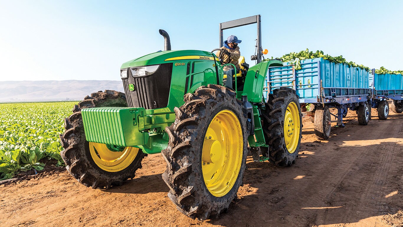 Un homme remorque ses récoltes avec un tracteur 6120EH.
