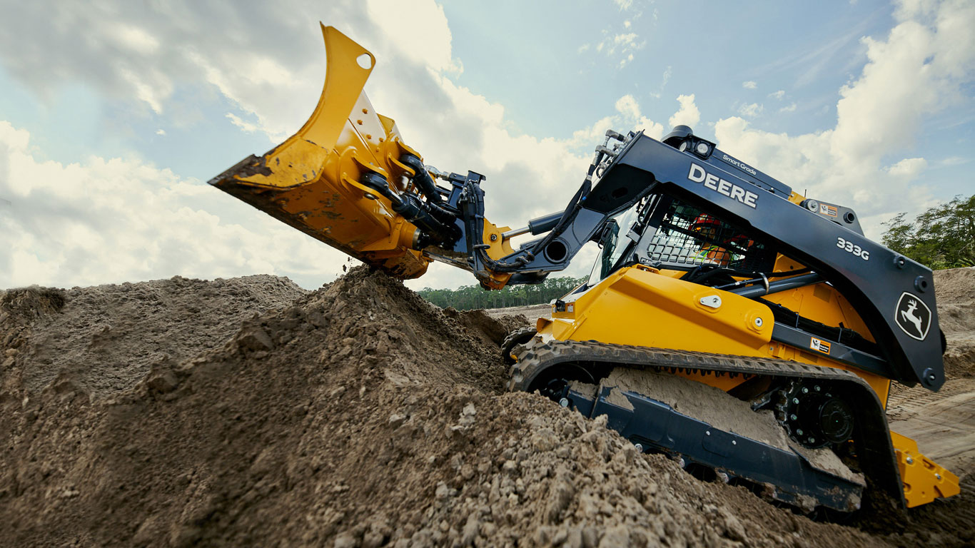 Side view of the industry’s first 333G SmartGrade Compact Track Loader in action on the jobsite