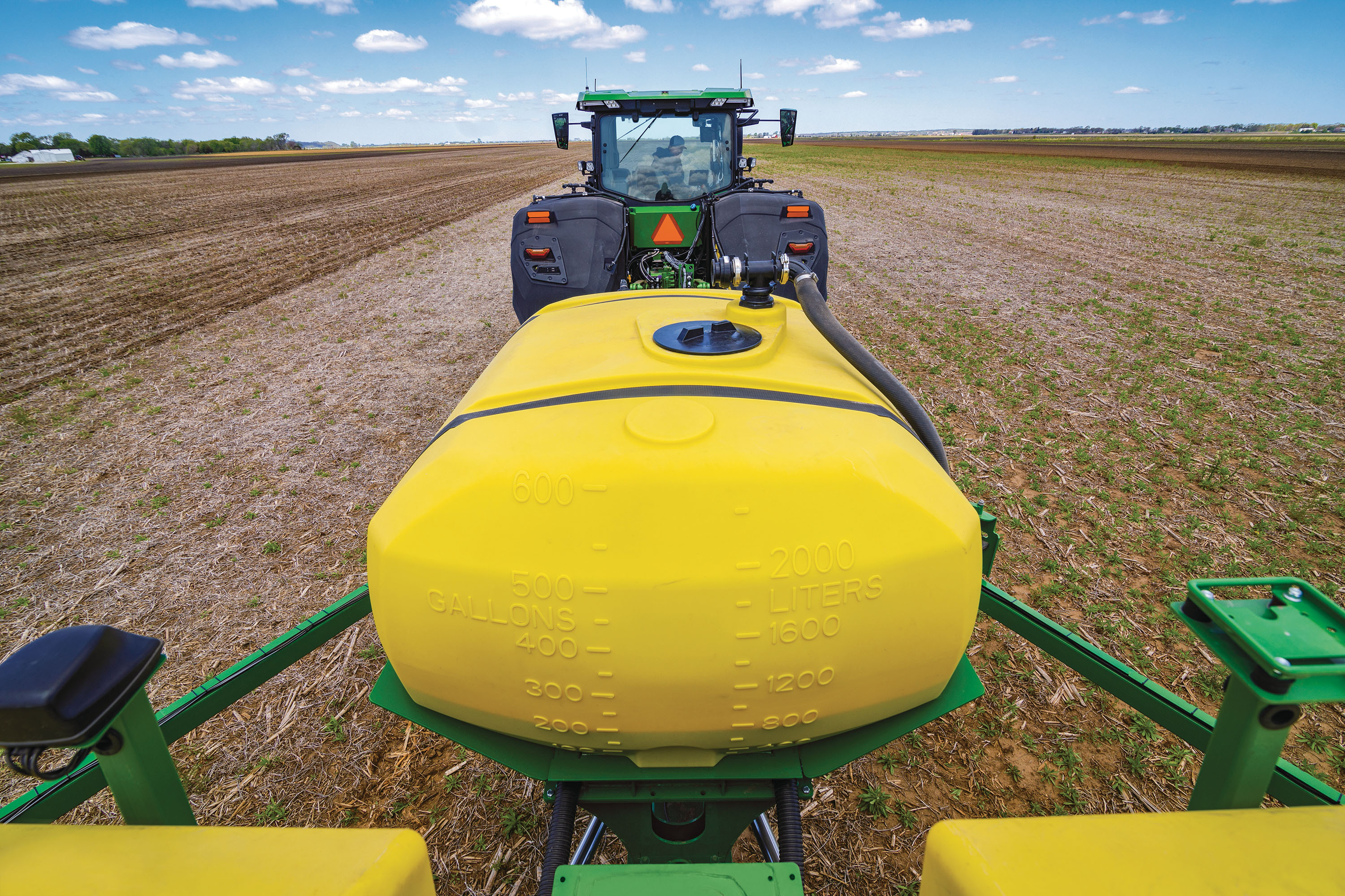 Vue arrière du réservoir pour denrées alimentaires derrière un tracteur dans un champ.