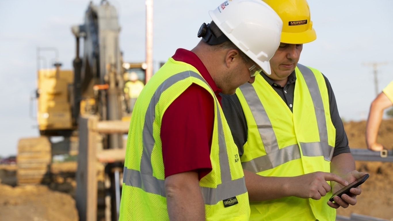 Large image of construction workers in the field using JDLink™ on a smartphone