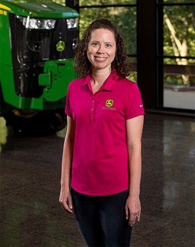 Heather Schladt stands in front of some John Deere equipment