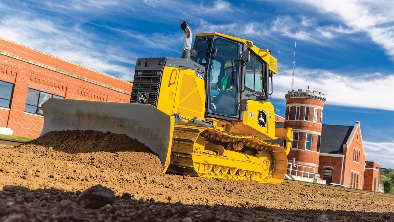 Large image or 650K Dozer with operator in cab on job site in from of brick building