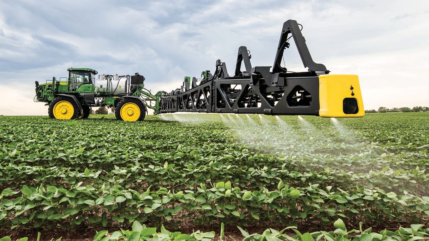 Gros plan d’une rampe de pulvérisateur John Deere dans un champ ouvert.