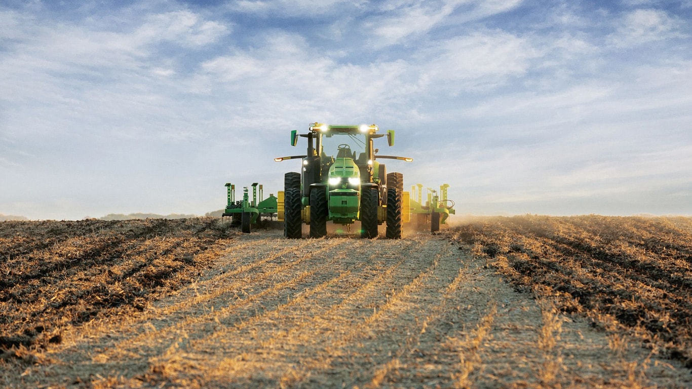 Tracteur John Deere autonome tirant de l’équipement de labourage dans un champ ouvert.