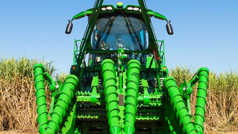 A closeup front view of the CH950 Sugar Cane Harvester parked in a sugar cane field