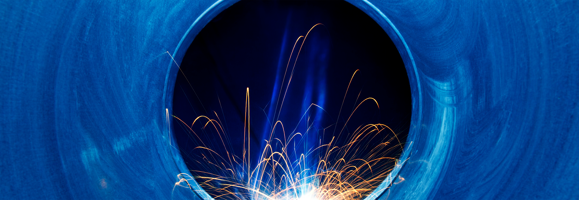 Sparks from a welder reflect off circular steel