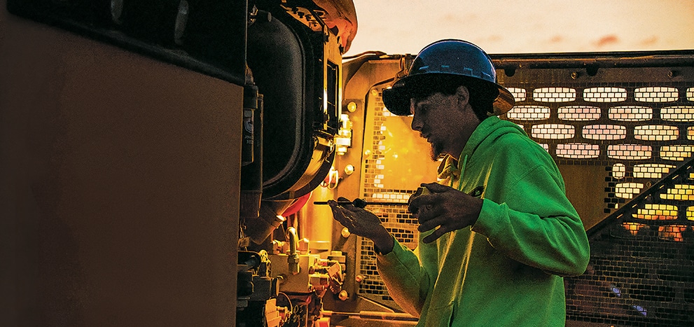 Un technicien de John Deere vérifiant l’huile d’une machine John Deere.