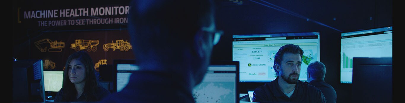 Analysts sitting at computers monitoring construction machine data