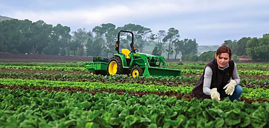 Une femme dans un champ avec un tracteur à l'arrière-plan