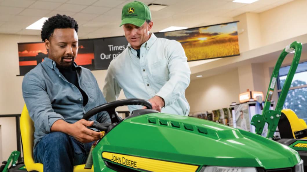 a Deere Dealer talking to a man on a mower