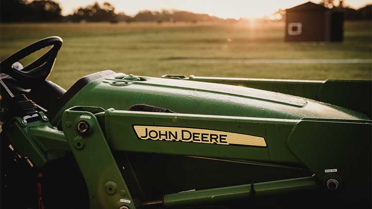 Close up of CUT tractor in a green field at sunset.