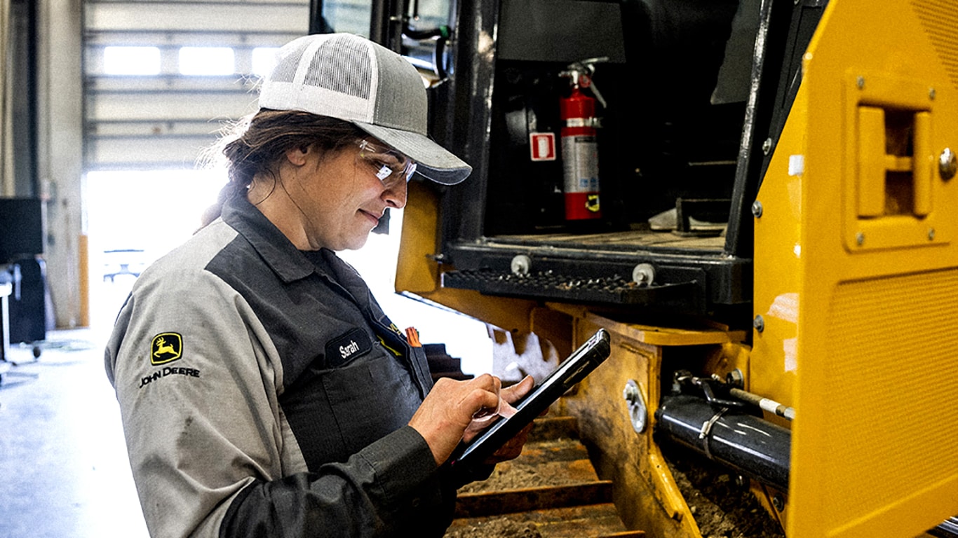 Technicien John Deere utilisant une tablette devant un équipement