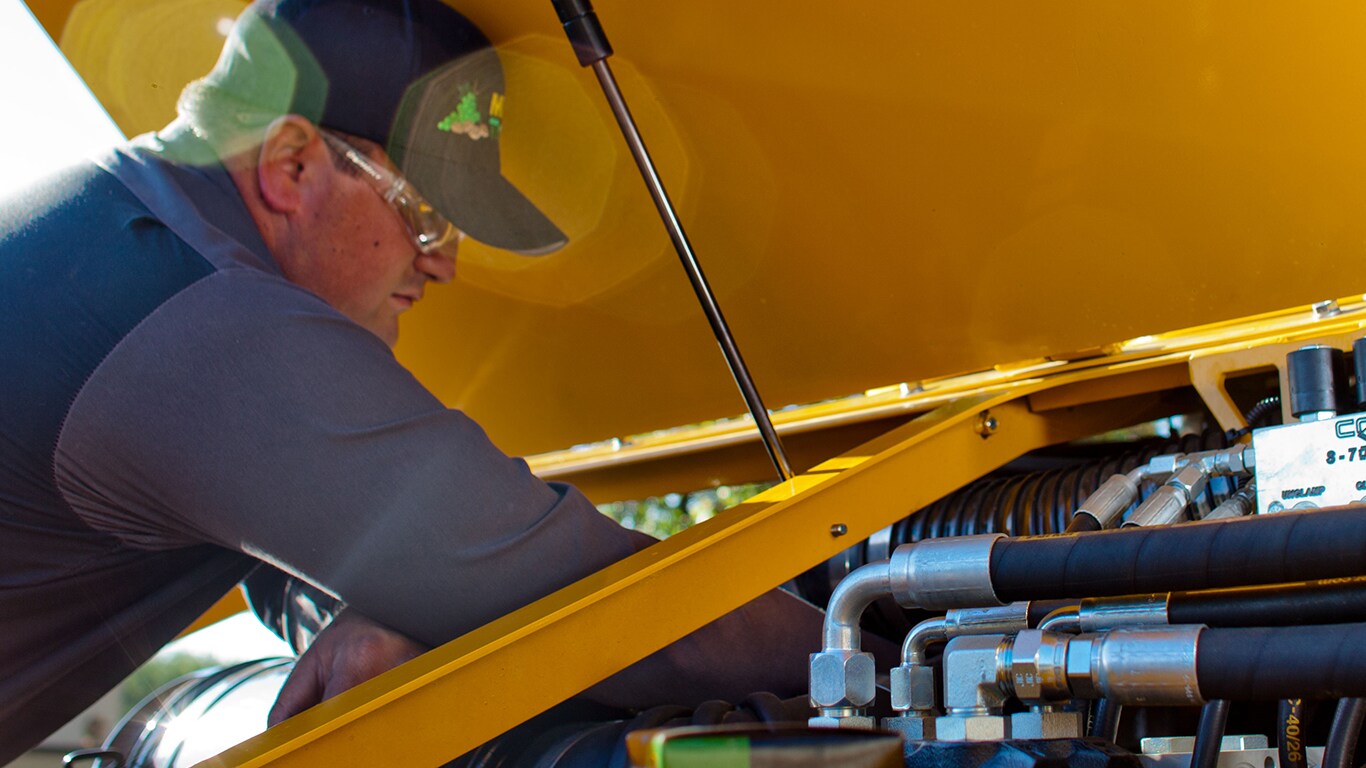 un homme travaillant sur un moteur sous un capot jaune