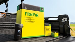 A variety of John Deere machine filters placed in the cargo bed of a Gator UTV.