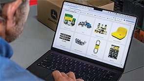 Person shopping for John Deere parts on a laptop.