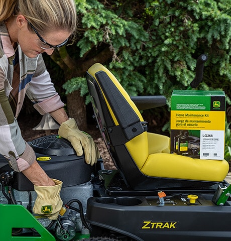 Person wearing gloves and safety glasses while working on a zero turn mower.