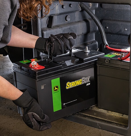 Gloved hands placing a battery into a machine.