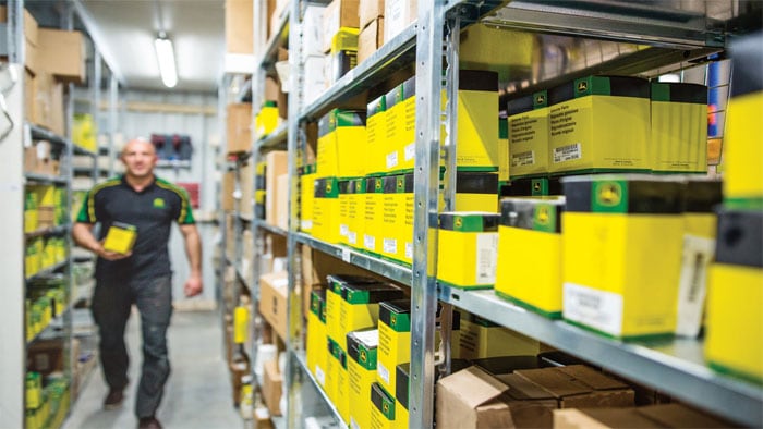 shelf stocked with commercial mowing parts with worker