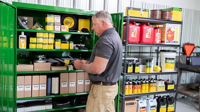 A man looking through his green parts storage locker