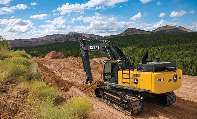 Une excavatrice 470G LC creuse une tranchée devant une chaîne de montagnes