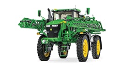 Self-propelled John Deere sprayer with elevated chassis and extended boom arms displayed on a white background.