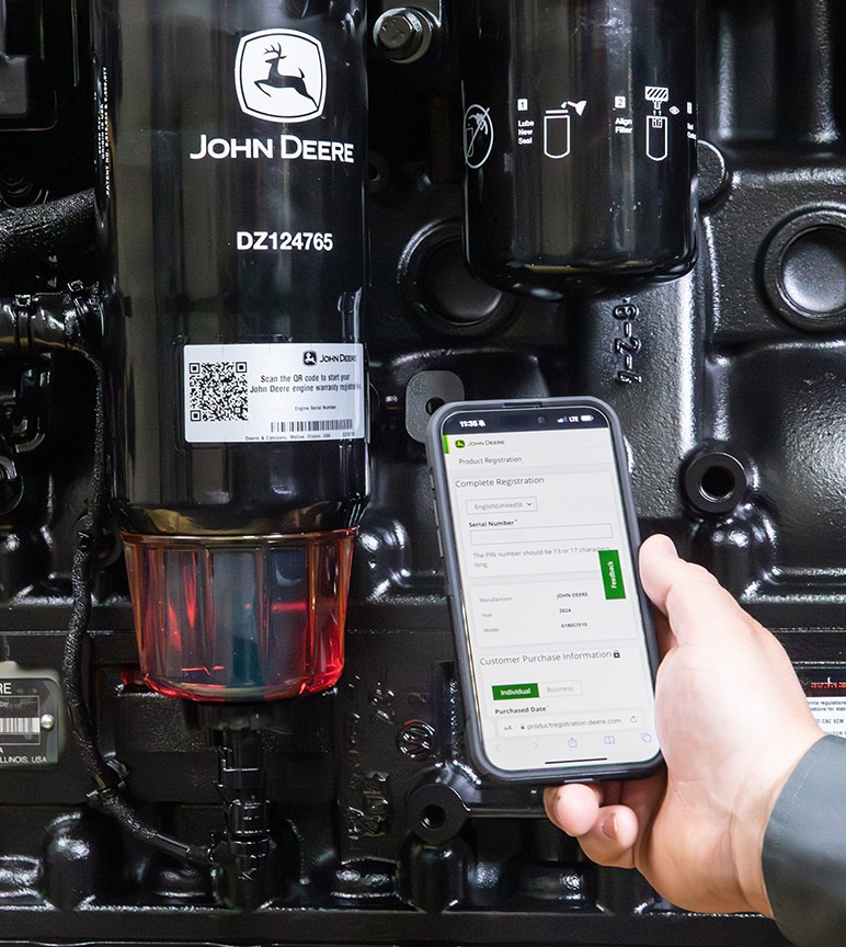 Smartphone displaying a warranty registration form beside a John Deere equipment serial number label and component assembly.