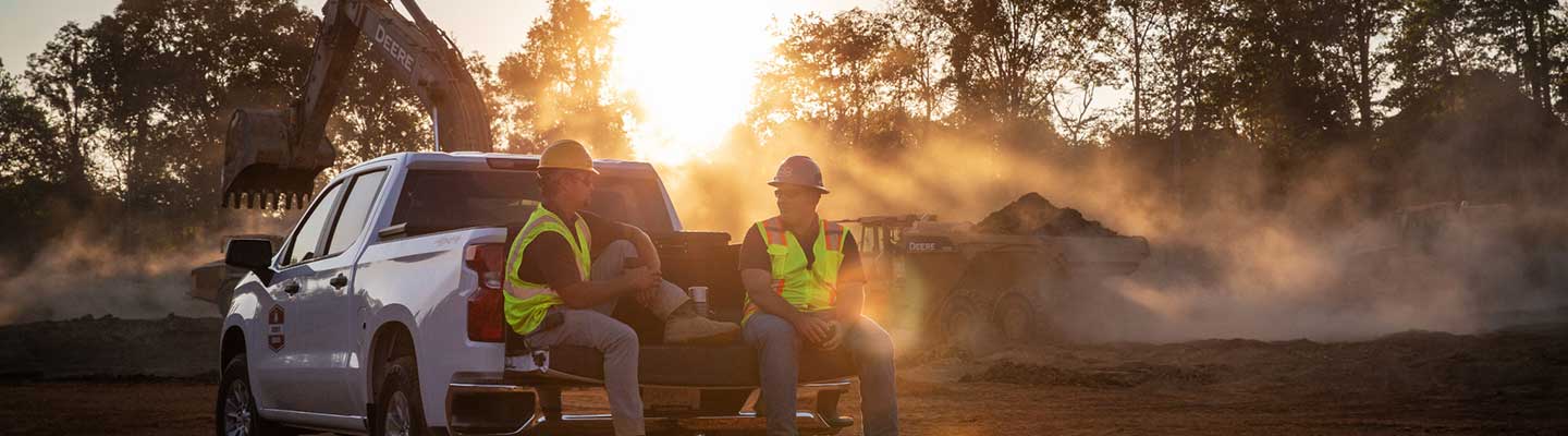 Deux personnes sont assises sur le hayon d'un camion de service concessionnaire au lever du soleil