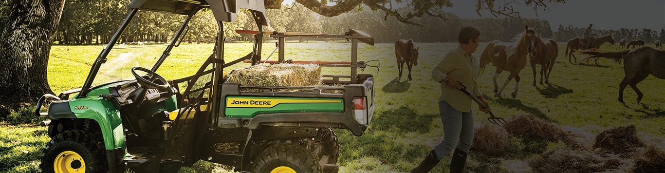 man feeding horses with hay on the back of the gator