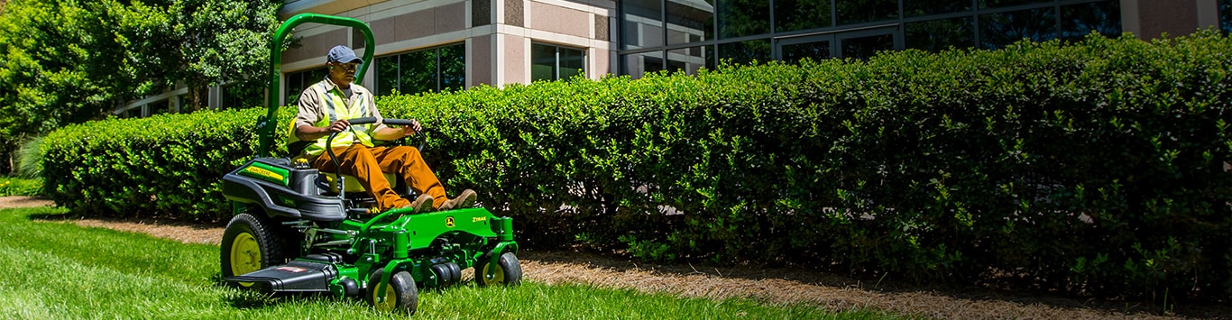 Man driving a z915e along a hedge