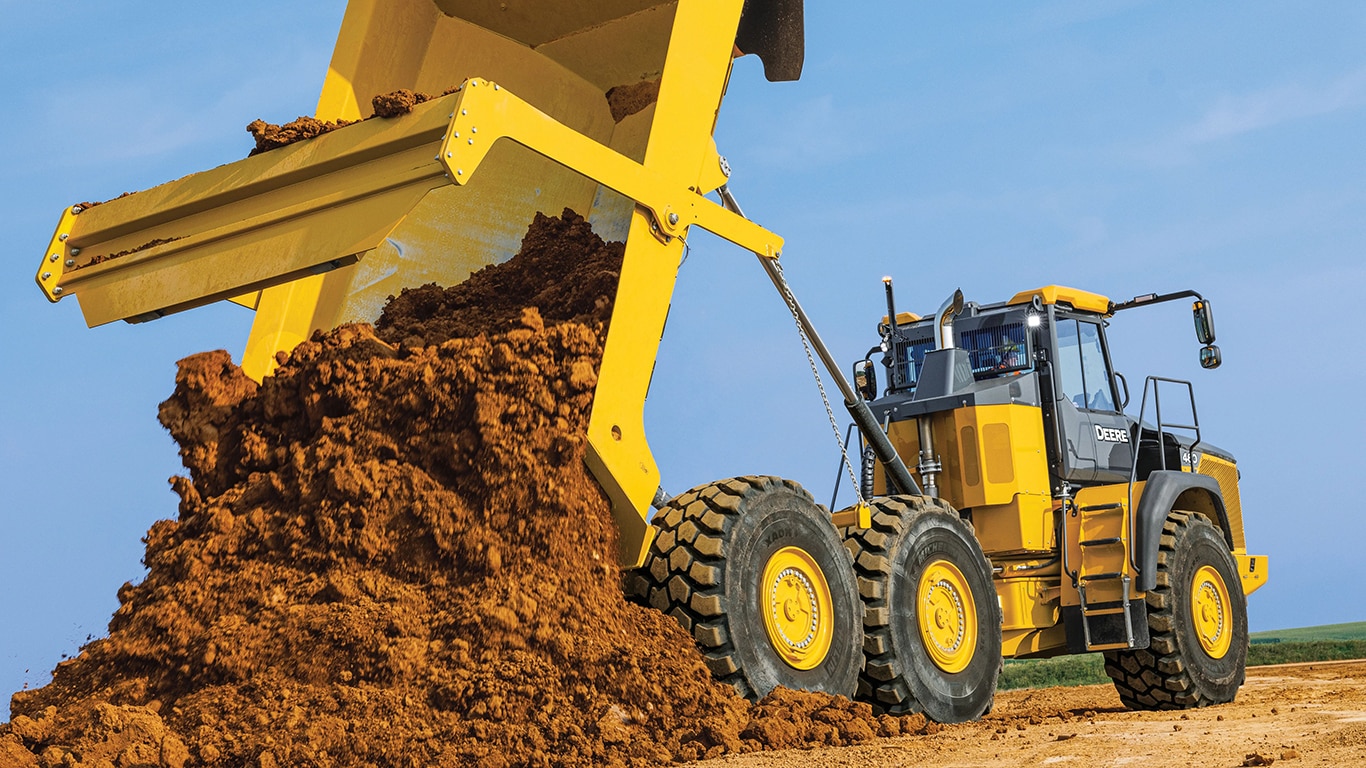 Un camion-benne articulé 460P déverse des saletés sur un chantier.