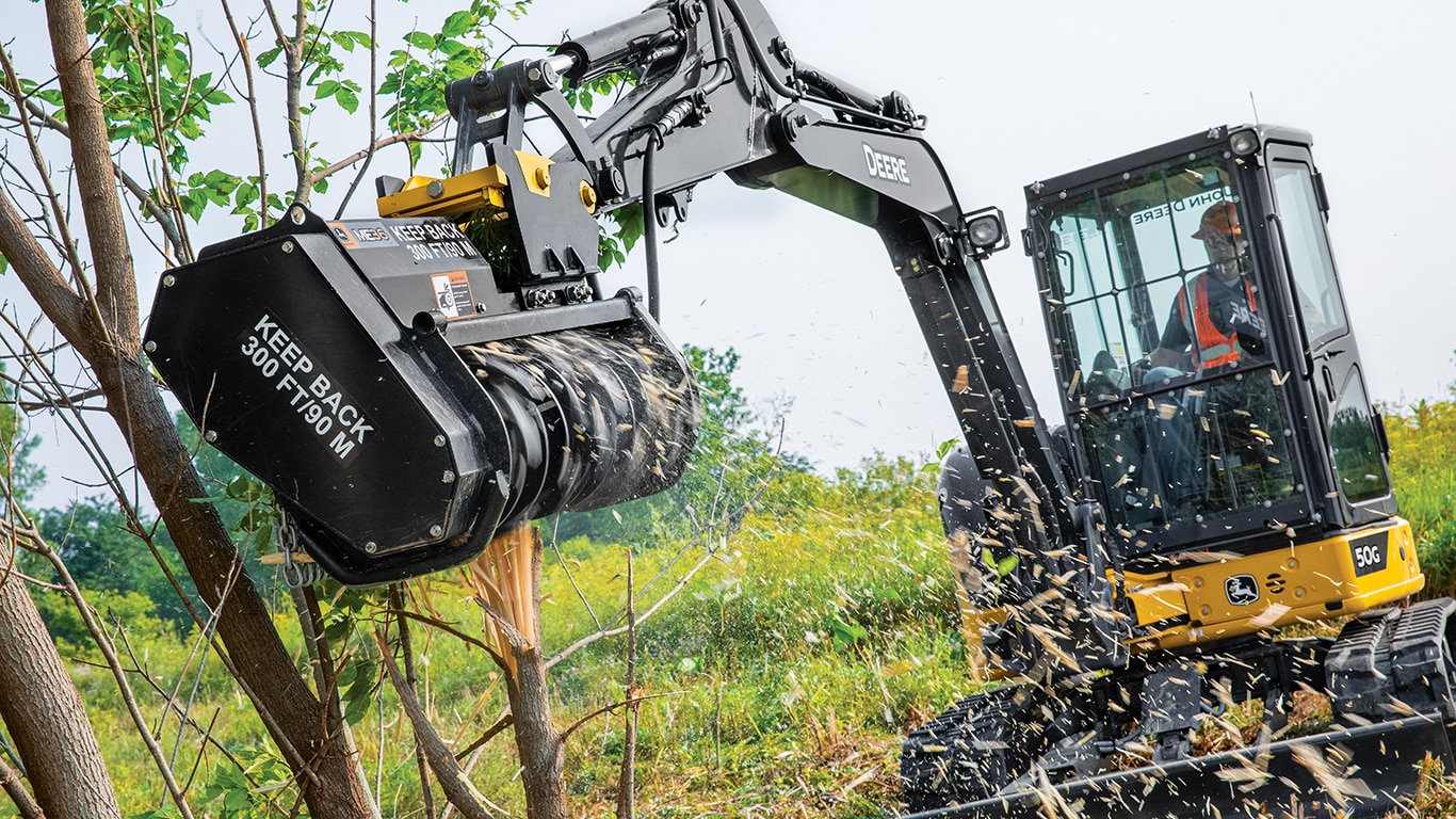 Compact excavator with mulching head works on a tree limb