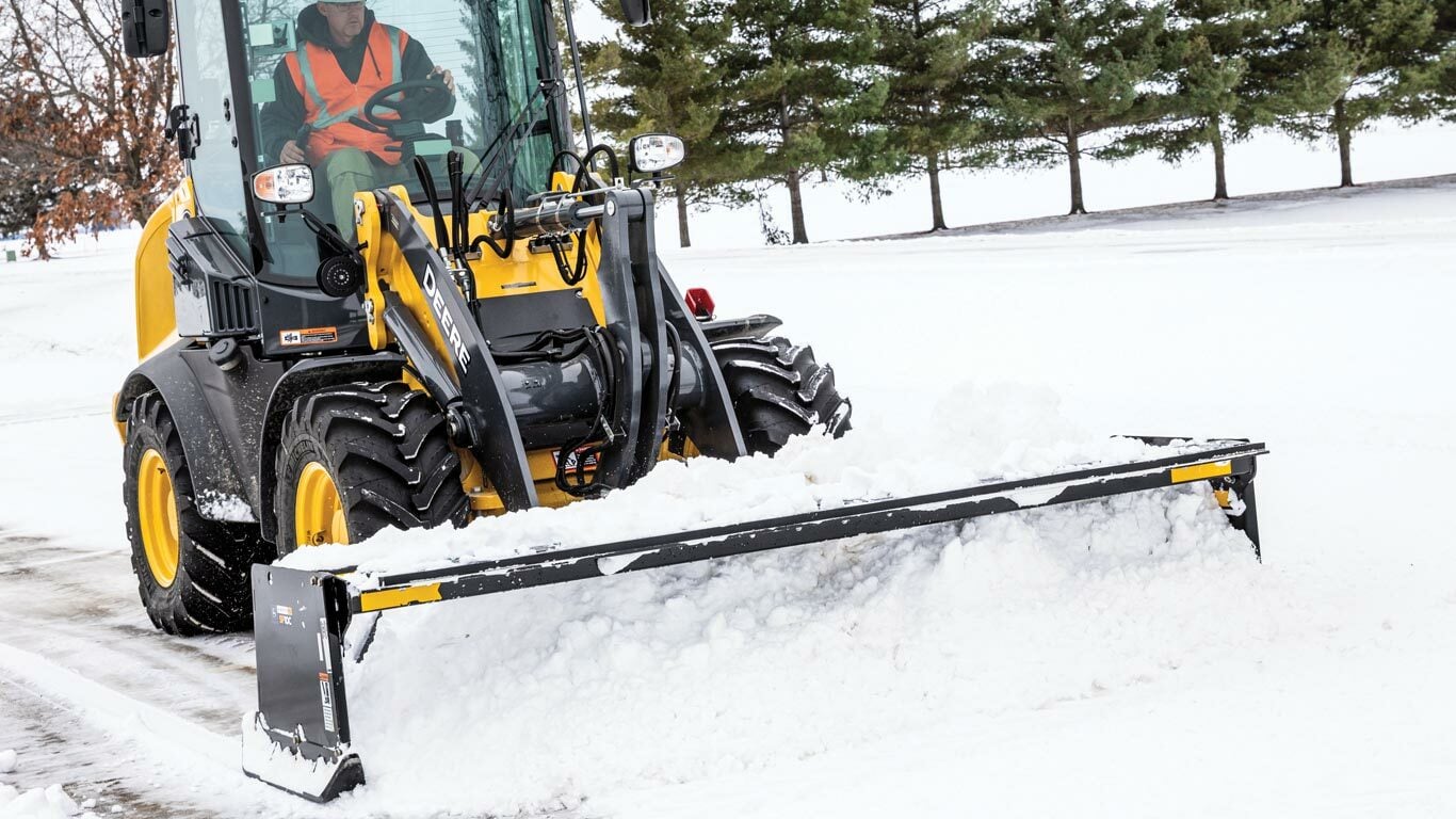 Chargeuse à quatre roues motrices 224L avec un accessoire pour pousse-neige SP10C poussant la neige dans un parc de stationnement