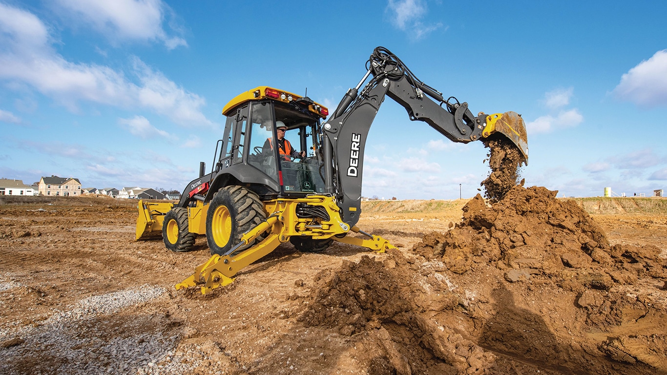 An operator dumping dirt from the boom of a 320P backhoe.