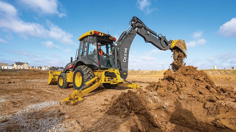 An operator dumping dirt from the boom of a 320P backhoe.