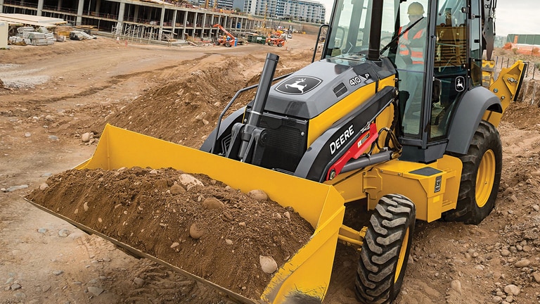 Une pelle-rétro 410P transportant de la terre sur un chantier de construction commerciale.