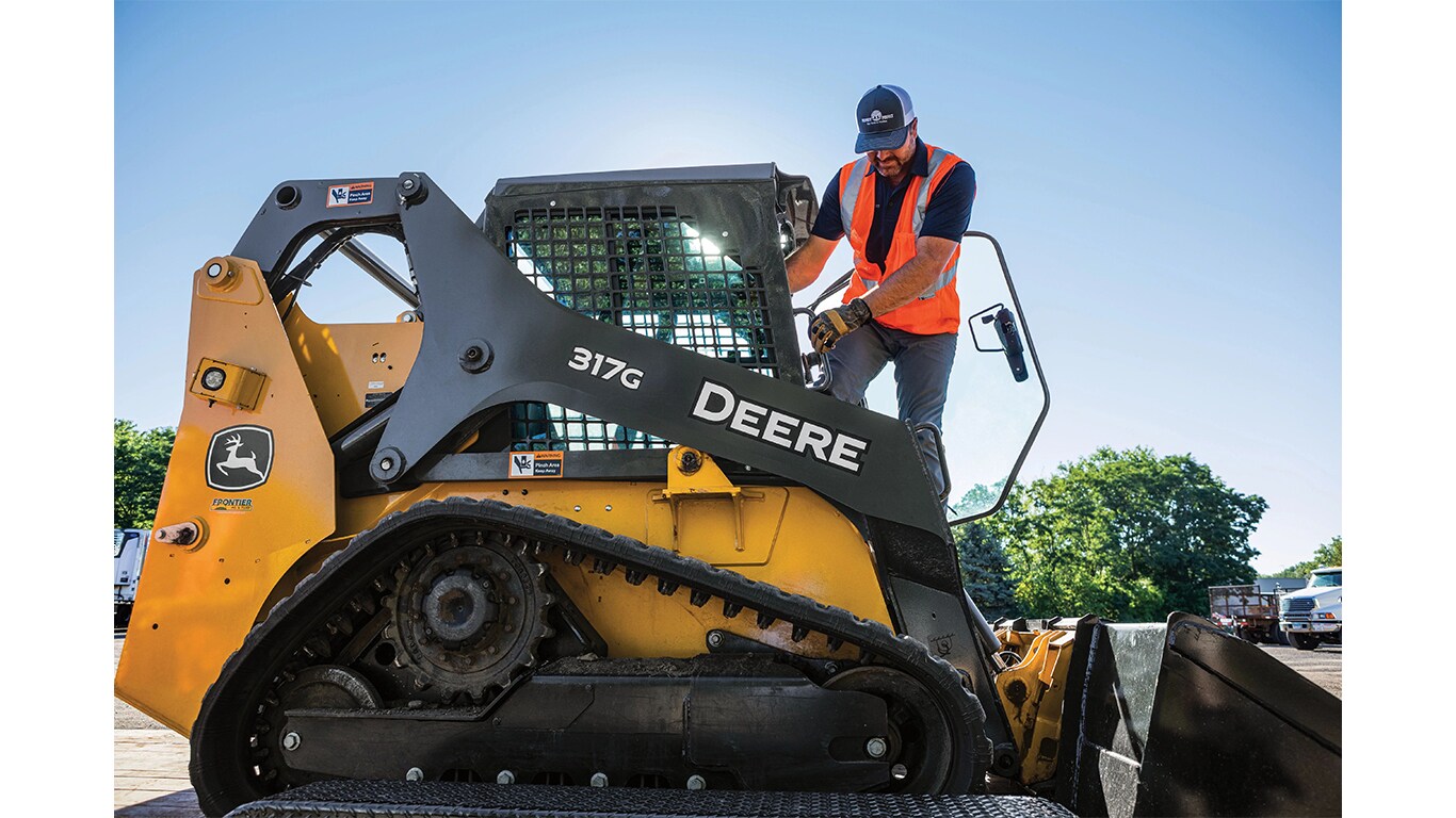 An operator climbing out of a 317G Compact Track Loader.