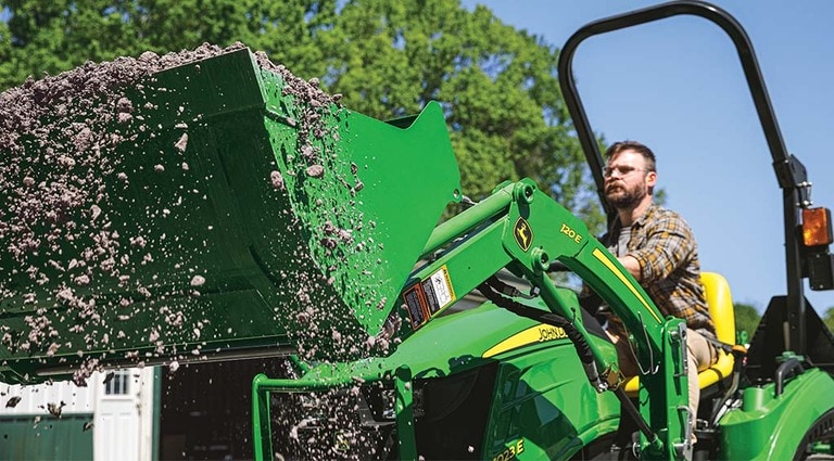 Une personne utilise son tracteur 1023E pour retirer des débris.