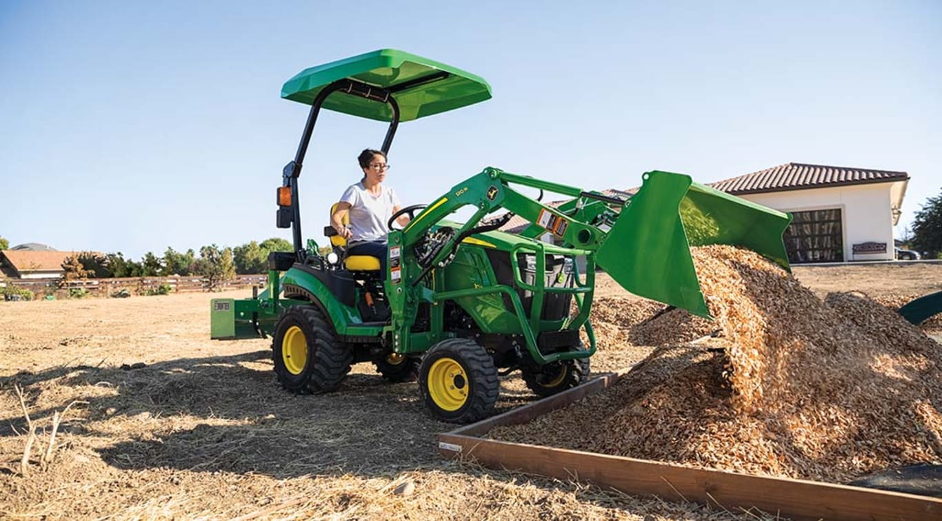 A person depositing saw dust using their 1025R Tractor.