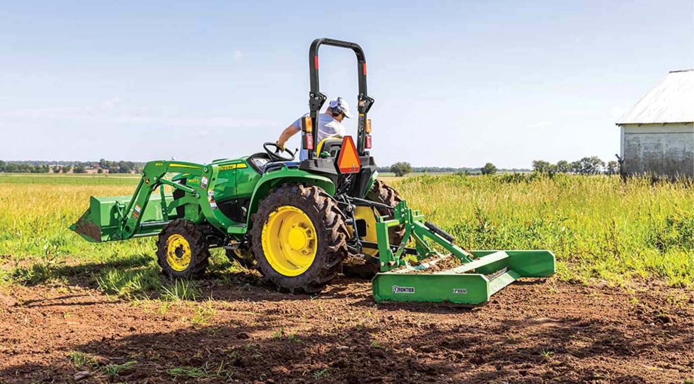 Une personne nivelant un terrain avec son tracteur 3025E.