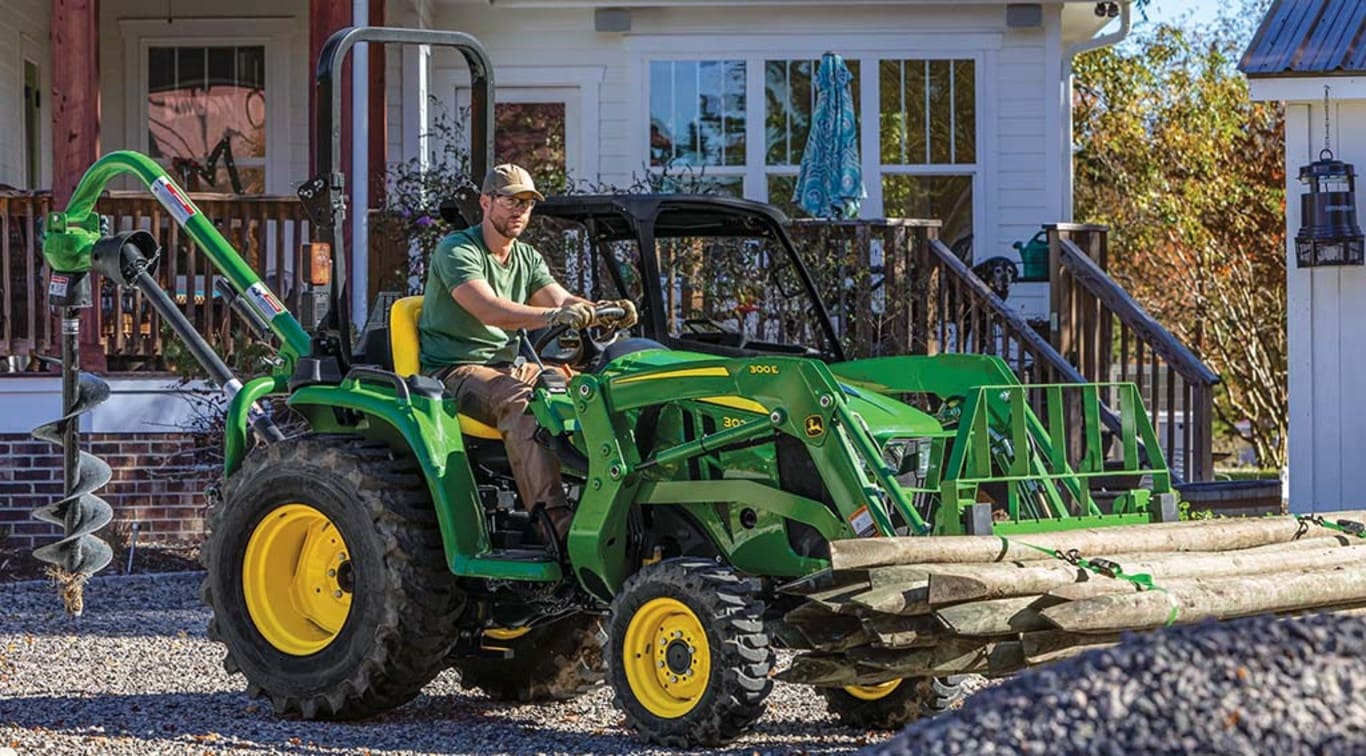 Une personne retirant des grumes d’un terrain en gravier avec son tracteur 3025E.