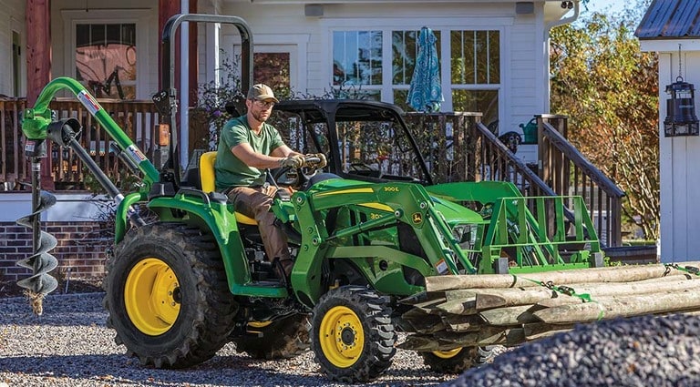 A person moving logs out of a gravel yard using his 3025E Tractor.