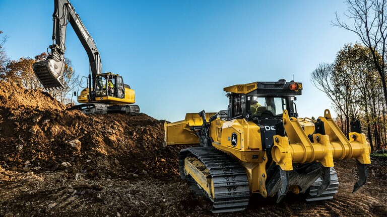 950 P-Tier dozer moving dirt on job site while John Deere excavator shovels.