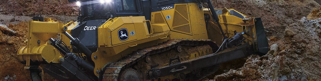 Bouteur chenillé John Deere déplaçant des tas de matériaux organiques.