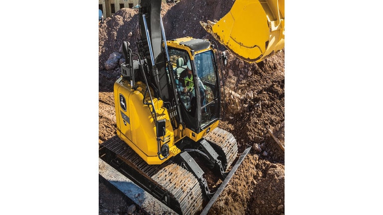 A side-view of the 135P-Tier Excavator surrounded by dirt piles.