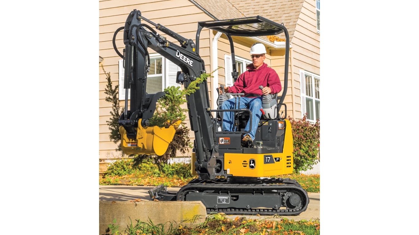 Man using 17P-Tier Excavator to move plants in front of a house.