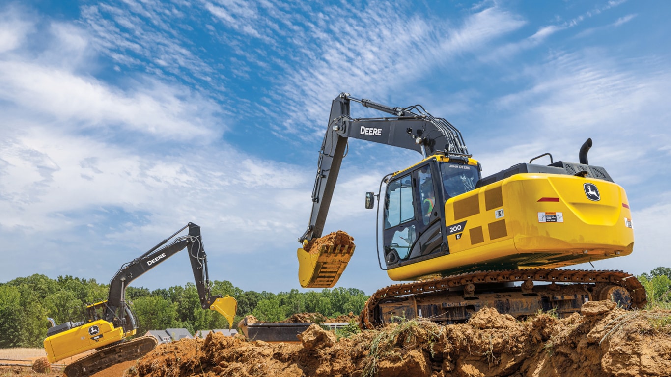 Une excavatrice 200G qui déplace de la terre sur un chantier avec une excavatrice 180P-Tier qui déplace également de la terre en arrière-plan.