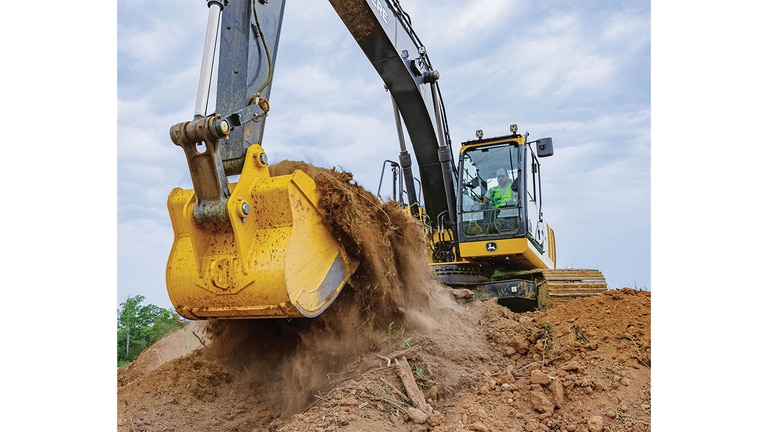An operator using a 210P-Tier Excavator to scoop dirt from the top of a stockpile.