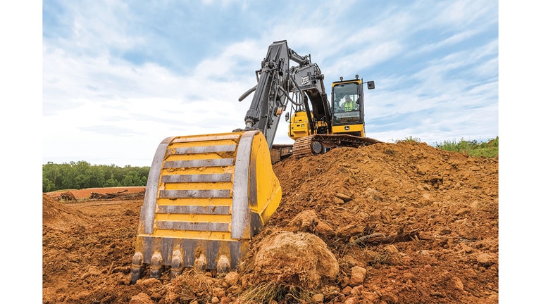 Gros plan du godet d’une excavatrice 210P-Tier récupérant la terre d’une pile de stockage.