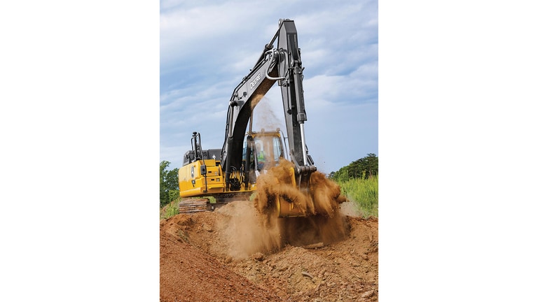 Un opérateur qui utilise une excavatrice 210P-Tier pour déplacer de la terre sur un chantier avec de l’herbe et des arbres en arrière-plan.