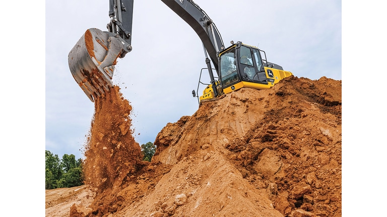 Une excavatrice 250P-Tier déverse de la terre dans une fosse à partir du sommet d’une pile de stockage.